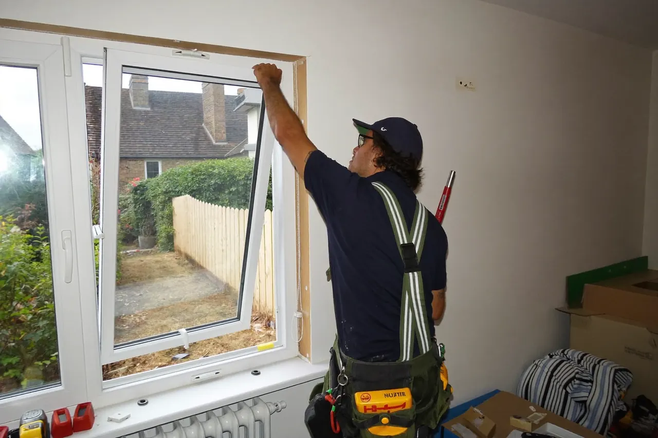 Installer lifting a new window frame into a prepared opening